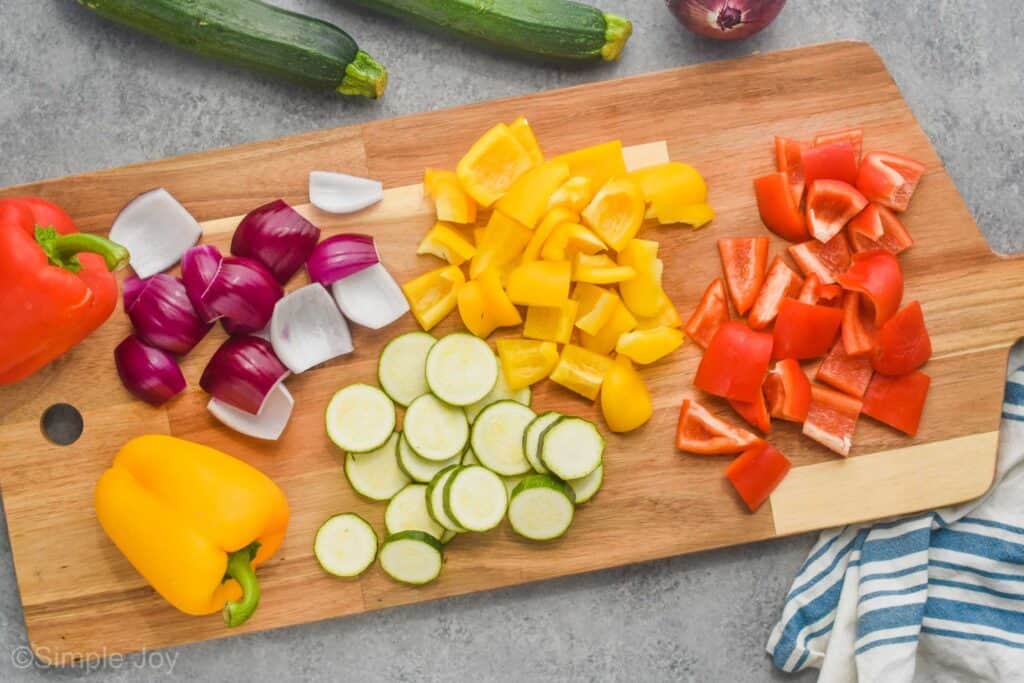 overhead view of a cutting board with cut up vegetables for chicken kabobs on it