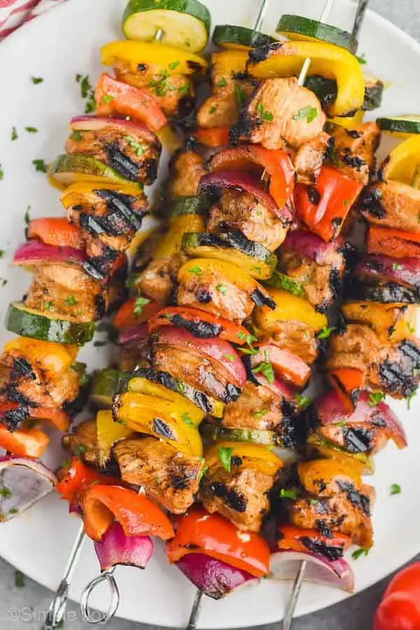 close up of chicken kabobs on a plate garnished with parsley