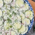 overhead view of a creamy cucumber salad garnished with fresh dill