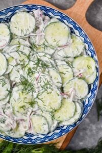 overhead view of a creamy cucumber salad garnished with fresh dill