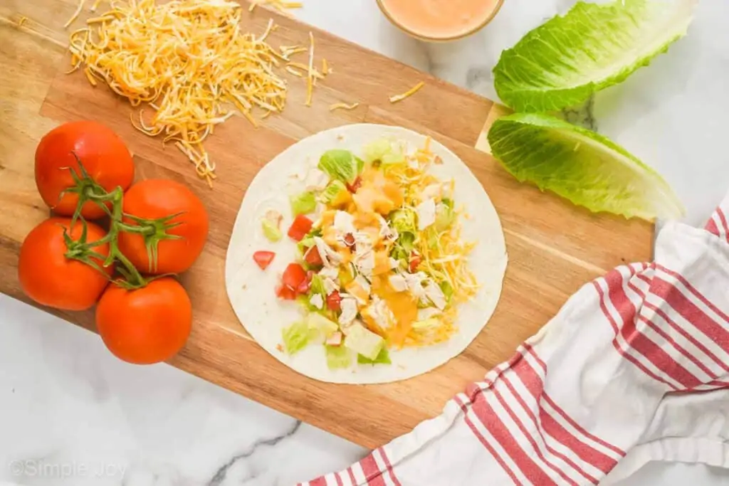 overhead view of a tortilla with ingredients for a chicken wrap