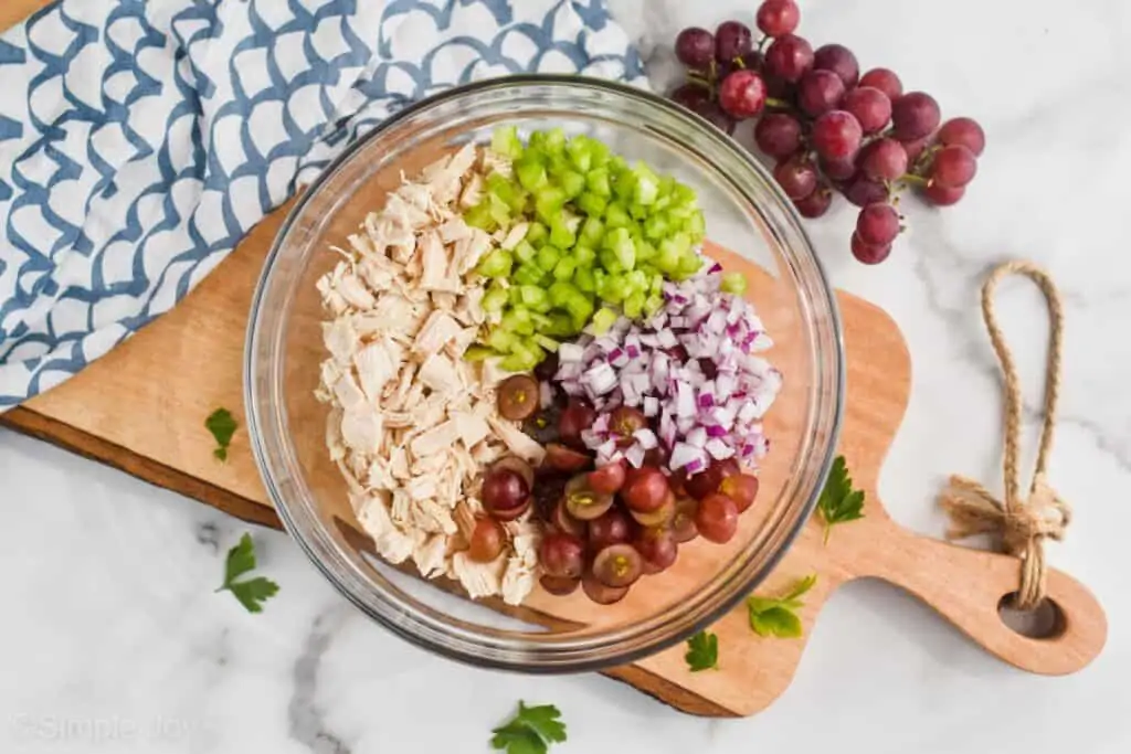 overhead of the ingredients for chicken salad broken up by ingredient in a bowl