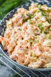 side view of a seafood salad garnished with fresh dill in a blue ceramic bowl