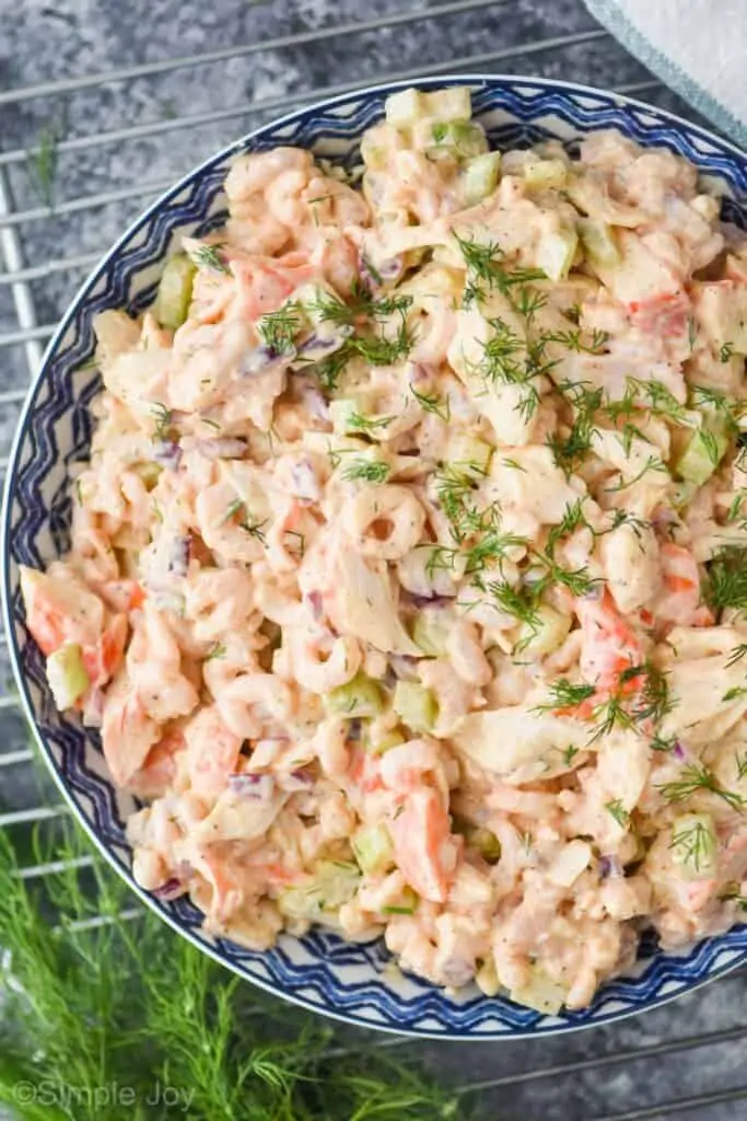 overhead view of a seafood salad in a ceramic bowl garnished with fresh dill