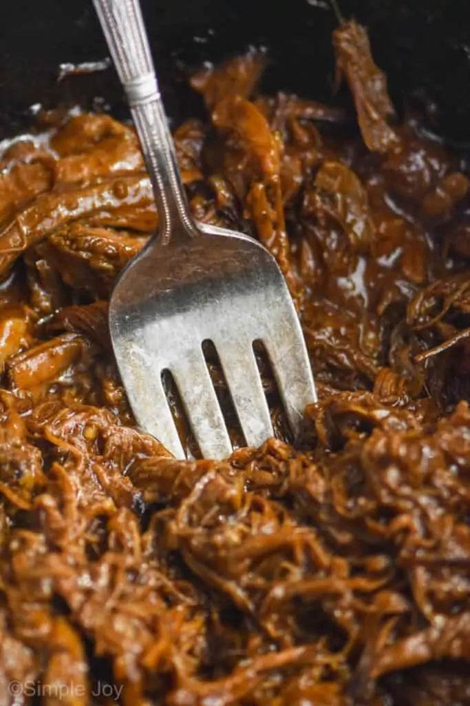 close up of a serving fork digging in to shredded bbq beef