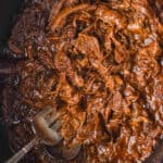 overhead of slow cooker bbq beef in a crockpot with a fork and spoon