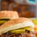close up of bbq beef recipe on a sesame seed bun with two pickles on it