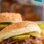 close up of bbq beef recipe on a sesame seed bun with two pickles on it