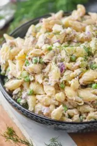 a tuna pasta salad in a bowl garnished with fresh dill