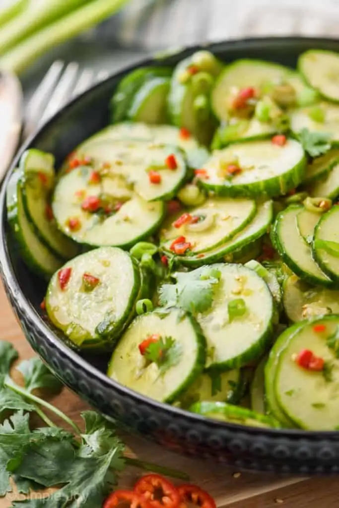 side view of asian cucumber salad in a dark serving bowl