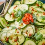 bowl of asian cucumber salad garnished with cilantro and extra slices of red jalapeño