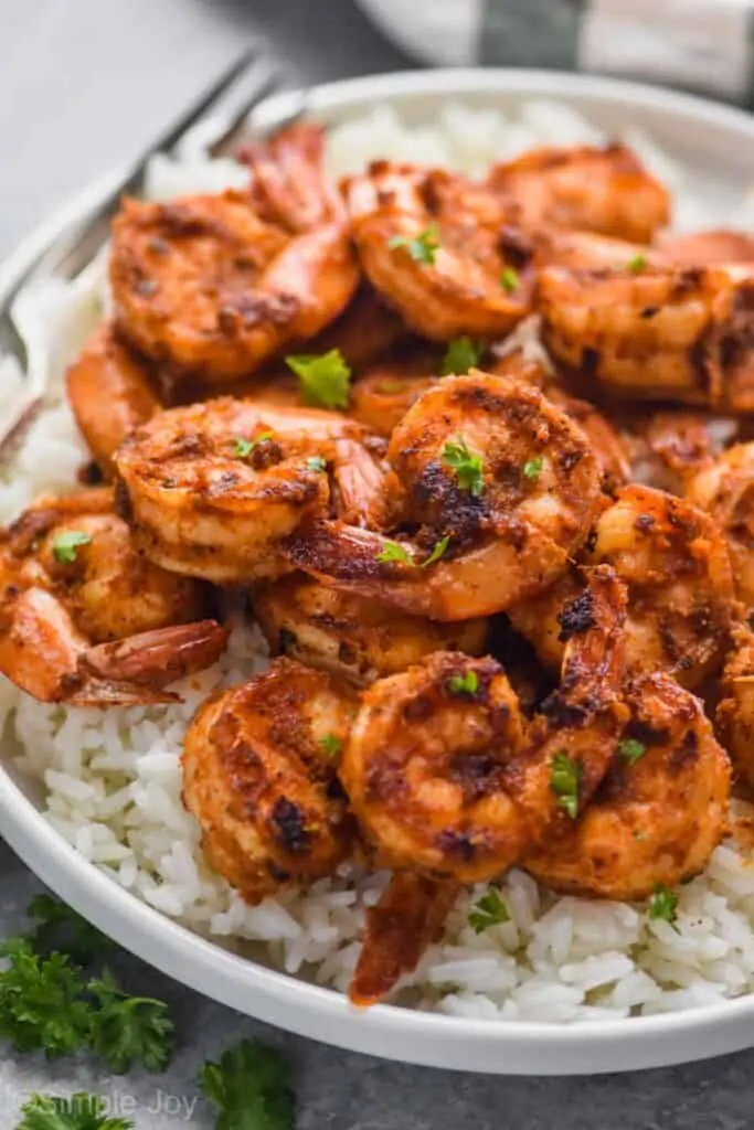 blackened shrimp recipe over white rice garnished with parsley bits