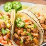 close up of a chicken taco on a plate with fresh jalapeño slice