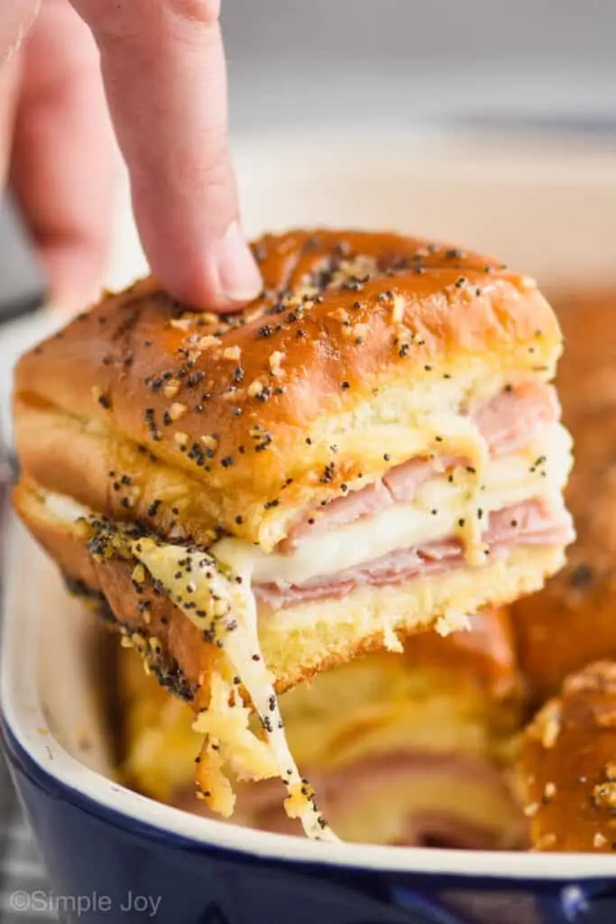 a ham and cheese slider being pulled out of a pan