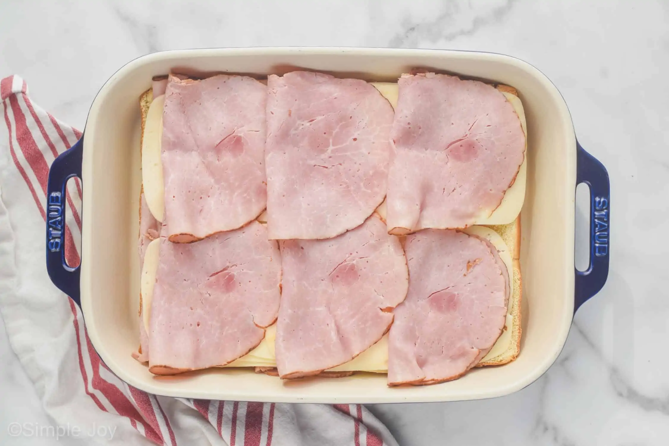 overhead of ham layered on Swiss cheese to make ham and cheese sliders