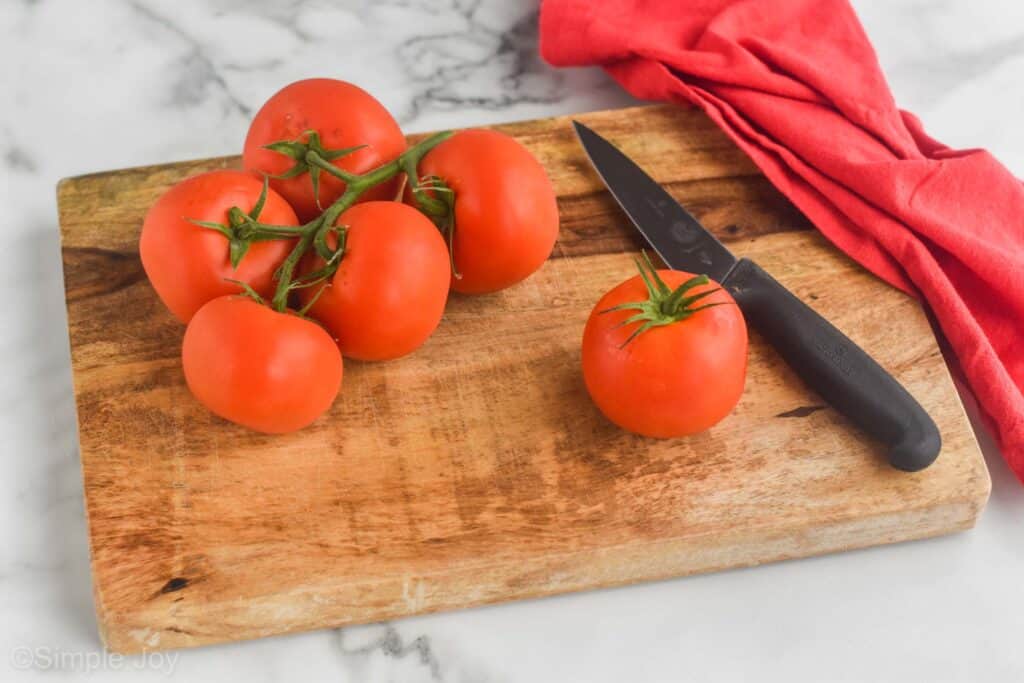tomatoes on a vine on a cutting board