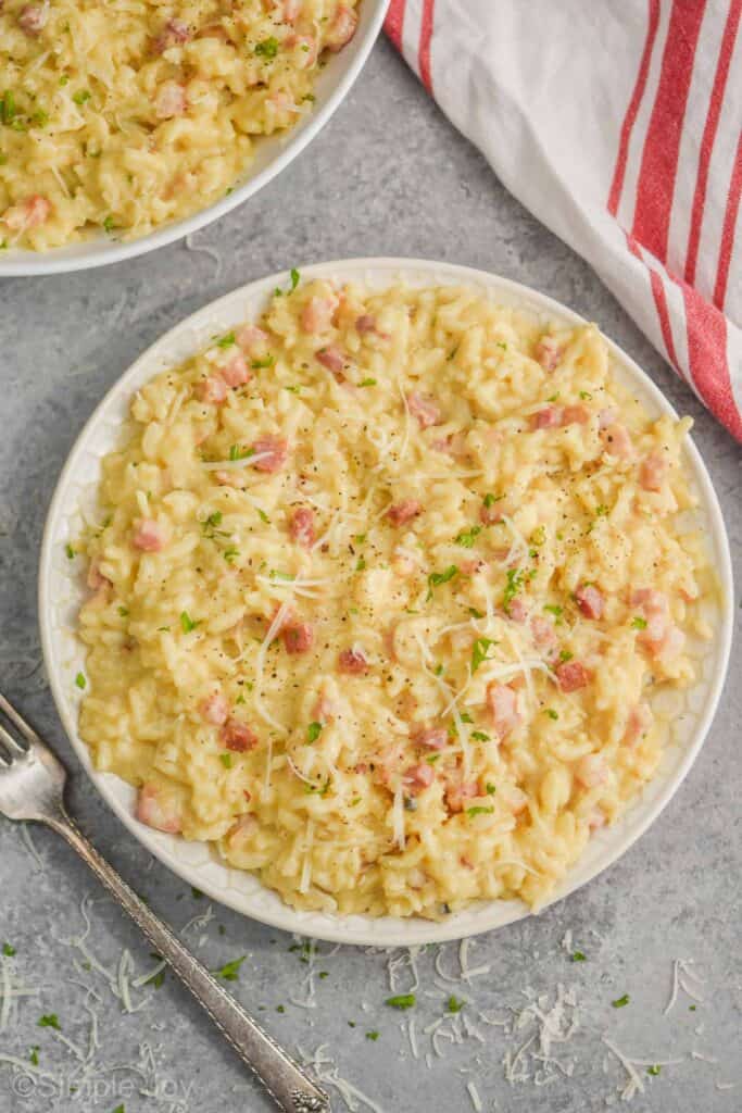 overhead of a small plate of instant pot risotto recipe, carbonara style with parmesan cheese, fresh black pepper and parsley