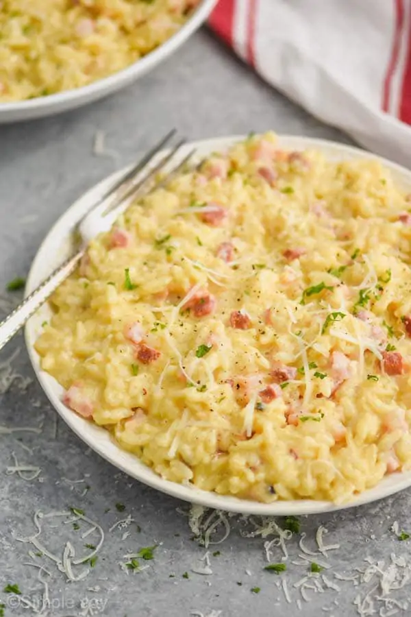 a small plate with instant pot risotto on it garnished with parsley and fresh parmesan