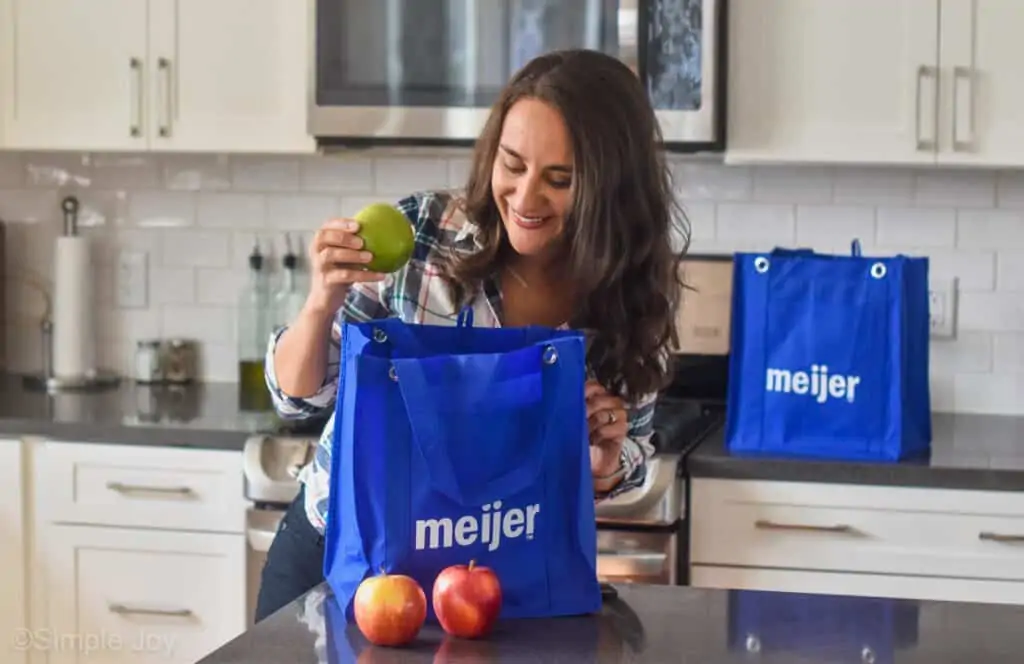 woman taking a apple out of a Meijer grocery bag