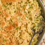 overhead view of a skillet full of tuna noodle casserole with a spoonful missing