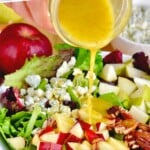 pinterest graphic of dressing being poured on a fall salad, says: "amazing apple fall salad simplejoy.com"