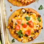 overhead view of a corn tortilla chicken tostada recipe garnished with diced tomatoes and cilantro