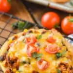 close up of a chicken tostada recipe on a wire cooling rack with diced tomatoes and fresh cilantro