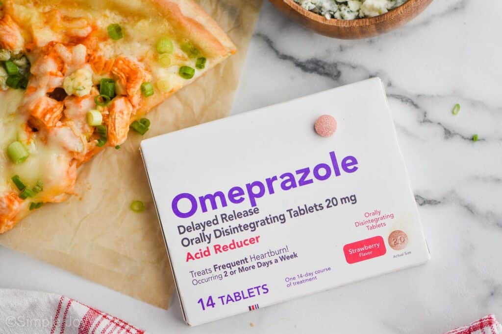 overhead view of a box of omperezole odd with one of the pink pills sitting on top of the box