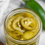 pinterest graphic of overhead view of jar of pickled jalapeños, says, "the best pickled jalpapenos simplejoy.com"