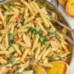 overhead view of a skillet with tuscan chicken pasta, and two slices of toasted garlic bread sticking into the pan