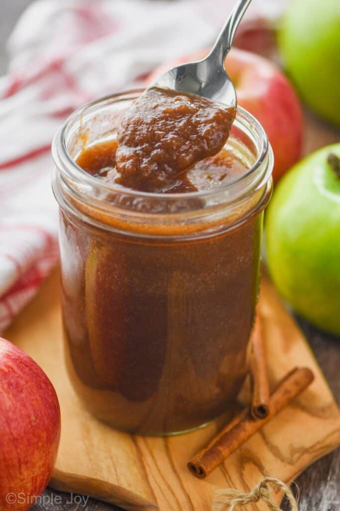 a small mason jar of an apple butter recipe that is being spooned up