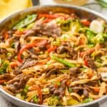 skillet of beef lo mein garnished with scallions and sesame seeds - 18