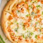 overhead of a Buffalo chicken pizza with one slice cut into, garnished with green onions
