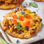 shredded chicken tostada on a rimmed baking sheet garnished with diced tomatoes and cilantro - 27