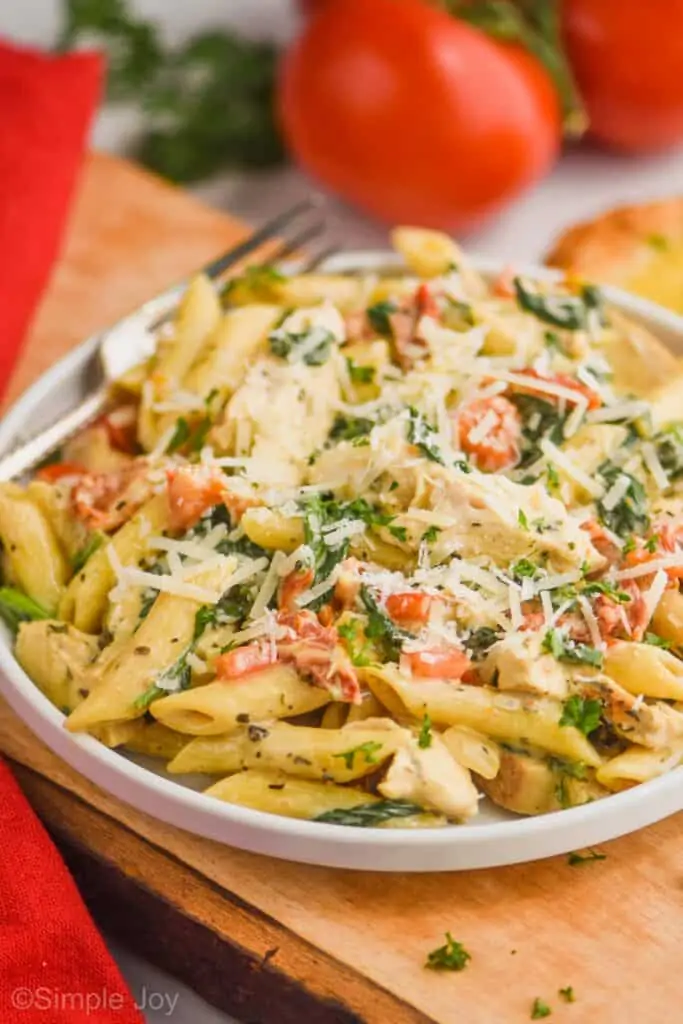 side view of a plate of tuscan chicken pasta garnished with parmesan cheese