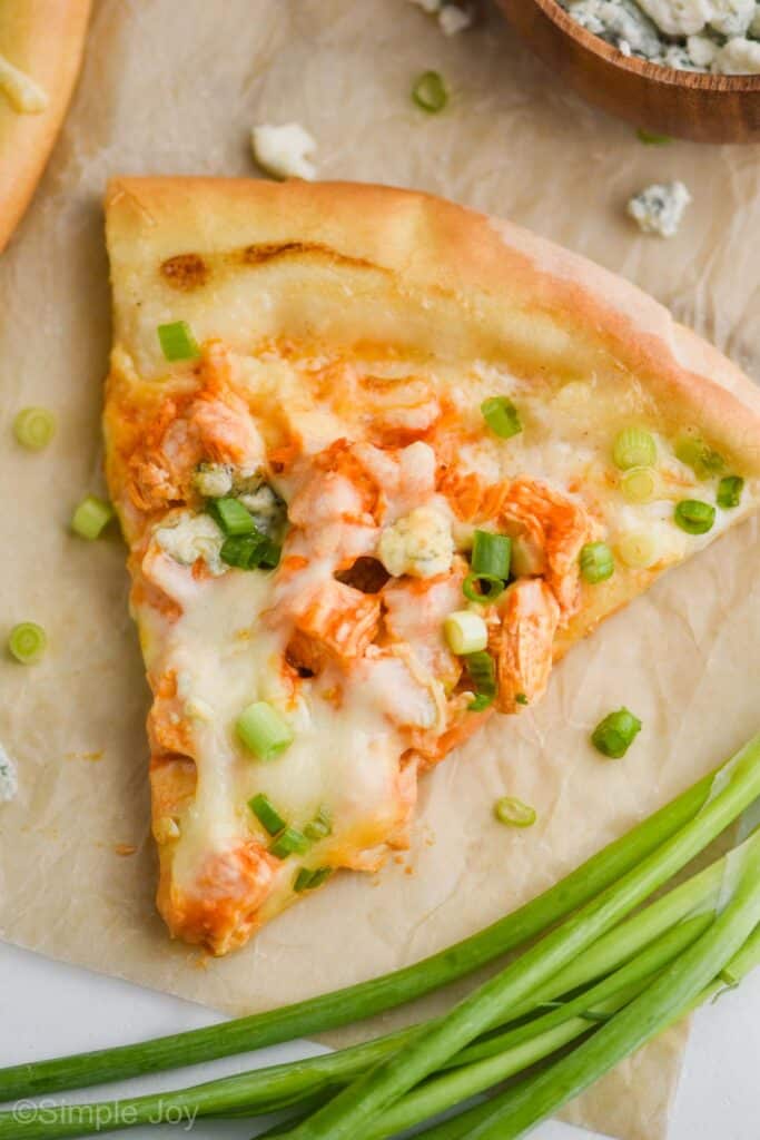 overhead of a piece of buffalo chicken pizza that has been garnished with green onion slices