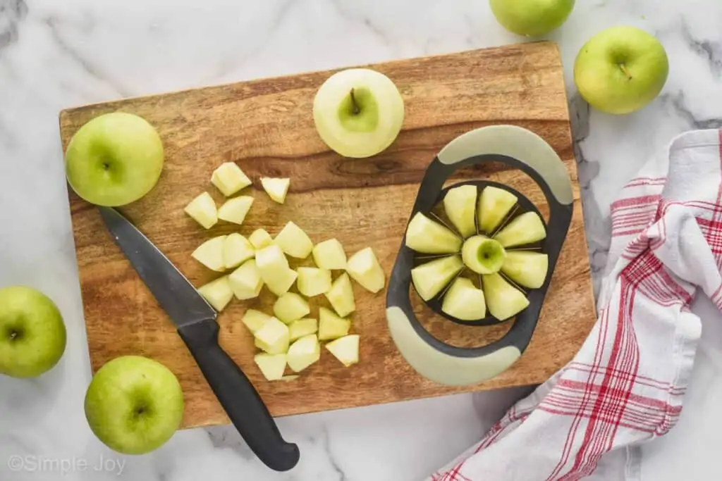 overhead view of a cutting board, cutting peeled apples with an apple corer