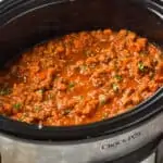 slow cooker bolognese in a crockpot garnished with fresh parsley