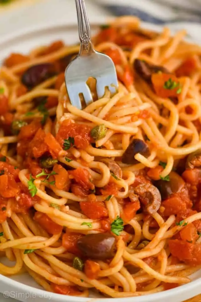 close up of puttanesca recipe being spun on a fork