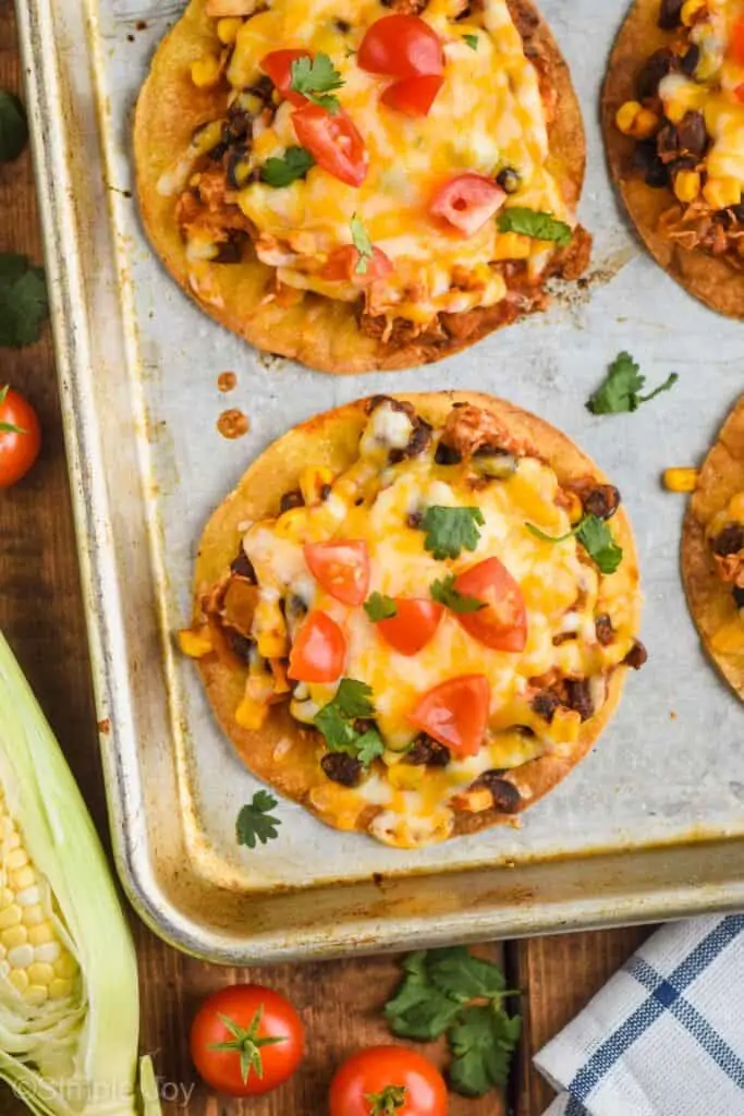 overhead view of a corn tortilla chicken tostada recipe garnished with diced tomatoes and cilantro