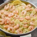 side view of a skillet full of shrimp scampi with angel hair pasta