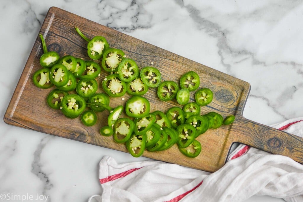 overhead of a cutting board full of sliced jalapeños