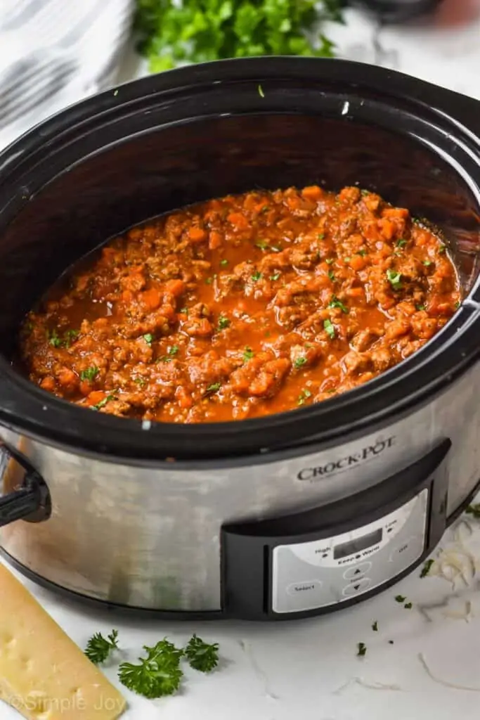 slow cooker bolognese in a crockpot garnished with fresh parsley