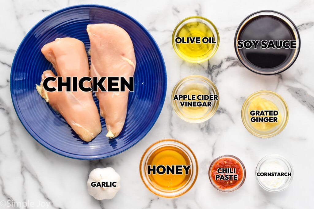 overhead of ingredients for sticky chicken in bowls and labeled: chicken, garlic, honey, apple cider vinegar, olive oil, soy sauce, ginger, cornstarch - 2