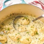 teal dutch oven full of easy chicken and dumplings garnished with fresh parsley