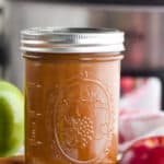 a mason jar full of applesauce in front of a slow cooker