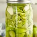 a mason jar full of pickled green tomatoes