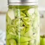 a mason jar full of pickled green tomatoes