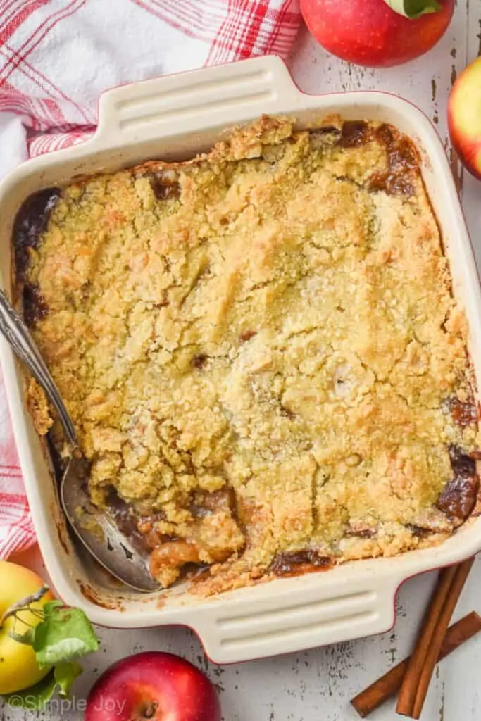 overhead view of square baking dish holding apple crisp recipe with a spoon digging in