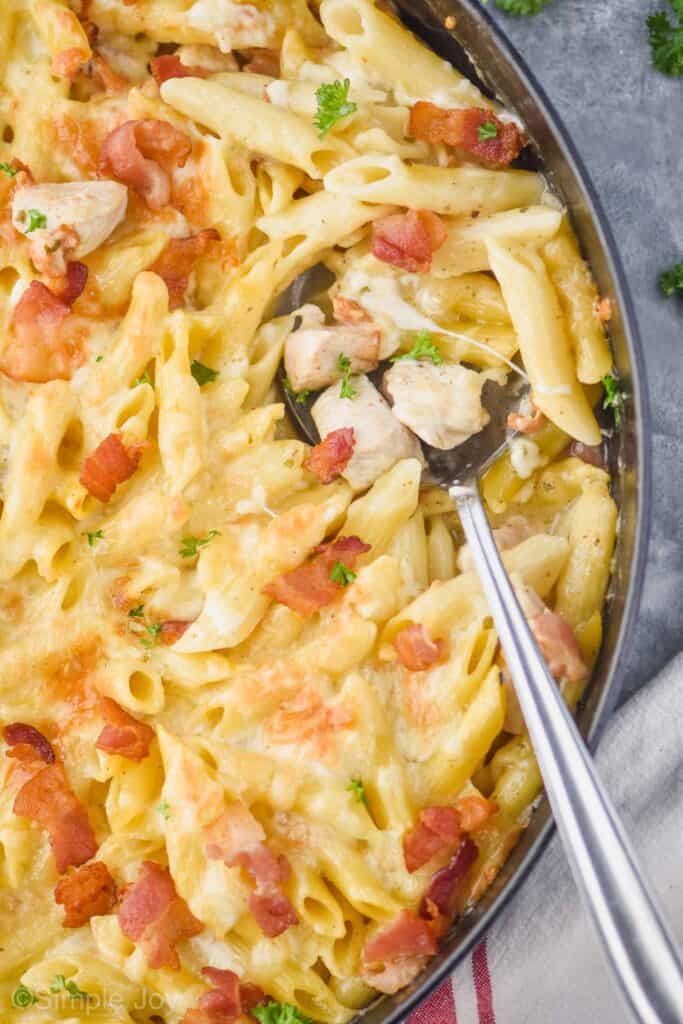overhead of chicken bacon ranch pasta being dished out of a large casserole dish